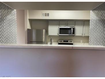 Open kitchen features stainless appliances, tile backsplash, and breakfast bar at 45 Maleena Mesa St # 1113, Henderson, NV 89074