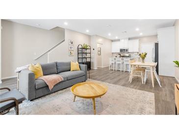 Cozy living room with a grey sofa, round wood table, and access to the open kitchen at 6239 Milford Sound St, Las Vegas, NV 89148