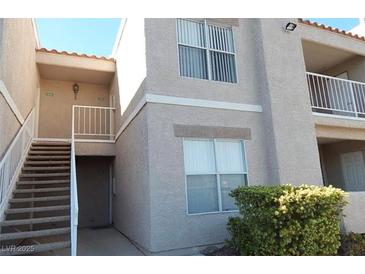 Condo exterior with tan stucco and stairs leading up to the units, showcasing balconies and well-maintained landscaping at 6800 E Lake Mead Blvd # 2050, Las Vegas, NV 89156