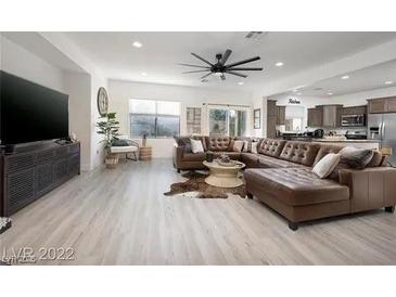 Bright living room with a brown leather sectional sofa, modern ceiling fan, and large flat screen TV at 11913 Alava Ave, Las Vegas, NV 89138