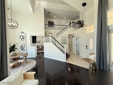 Bright, open-concept living space with high ceilings, dark wood floors, and a view of the staircase at 2429 Worchester Rd, Henderson, NV 89074