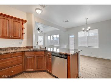 A kitchen featuring wood cabinetry, granite countertops, stainless steel appliances, and a breakfast bar at 2612 Kindness Ct, North Las Vegas, NV 89031