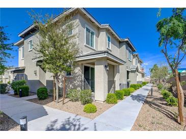 Charming two-story townhome with a well-maintained walkway and inviting curb appeal on a bright, sunny day at 5730 Sky Pointe Dr # 104, Las Vegas, NV 89130