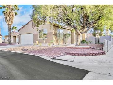 Tan single story home with a white garage door, desert landscaping and a large shade tree in the front yard at 7909 Smokey Ridge Ct, Las Vegas, NV 89131
