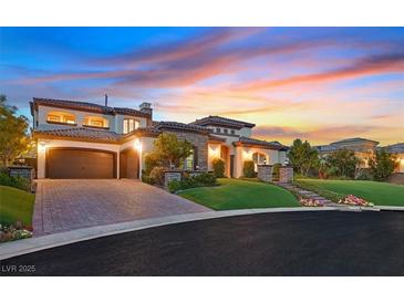 Stunning two-story home features a grand entrance, manicured landscaping, and a three-car garage with a brick driveway at 10 Olympia Outlook Dr, Las Vegas, NV 89141