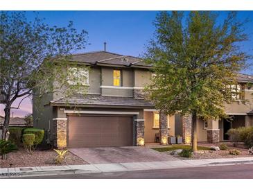 Charming two-story home featuring a two-car garage, stone accents, and manicured landscaping at 10305 Turia Gardens Rd, Las Vegas, NV 89135