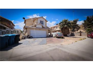 Two-story tan home with a two car garage, and a tile roof, under a sunny blue sky at 3871 Sir Bret Ct, Las Vegas, NV 89104