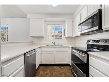 A well-lit kitchen features white cabinetry and stainless steel appliances at 6857 Tamarus St # 202, Las Vegas, NV 89119