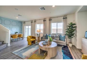 Bright living room with gray sofa, colorful rug, modern furniture, and large windows with stylish curtains at 7915 Pandora Sky St # 402, Las Vegas, NV 89084
