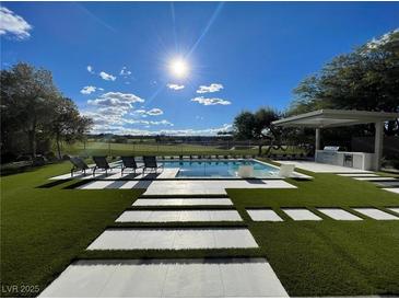 A backyard pool is surrounded by lush landscaping and offers picturesque golf course views at 5 Clear Crossing Trl, Henderson, NV 89052