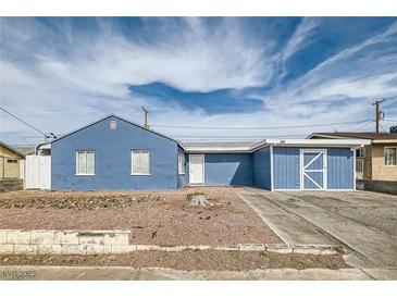 Charming single-story home with blue exterior, desert landscaping, and a driveway leading to an attached garage at 143 Constitution Ave, Henderson, NV 89015