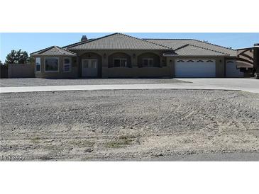 Sprawling single-story home with a large driveway, desert landscaping, and a tile roof at 3020 Peggy Ave, Pahrump, NV 89048