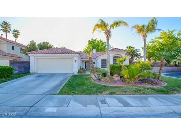 Charming single-story home featuring lush green grass, palm trees, and a well-maintained two car garage at 4517 Inez Dr, Las Vegas, NV 89130