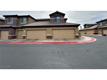 A tan condo complex featuring individual garages for each unit and tile roofing at 6868 Sky Pointe Dr # 2013, Las Vegas, NV 89131