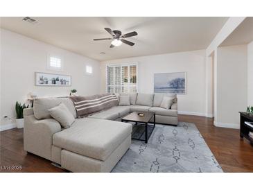 Bright living room features an oversized sectional, ceiling fan, and gorgeous hard wood floors at 3239 Robins Creek Pl, Las Vegas, NV 89135