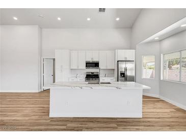 Bright kitchen features white cabinets, modern stainless appliances, and quartz countertop island at 689 Hitchen Post Dr, Henderson, NV 89011
