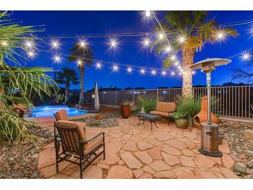 Inviting backyard patio with string lights, desert landscaping, pool, and comfortable seating, perfect for outdoor entertaining at 8113 Bay Colony St, Las Vegas, NV 89131
