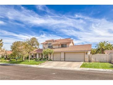 Charming two-story home boasts a three-car garage and manicured front lawn with mature trees at 1009 Nawkee Dr, North Las Vegas, NV 89031