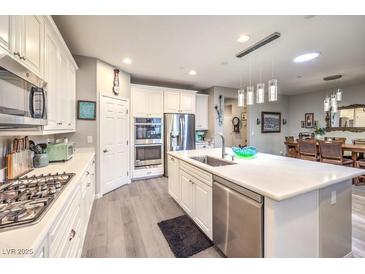 Bright kitchen features stainless steel appliances, white cabinetry, and a large kitchen island at 797 Drammatico Pl, Henderson, NV 89011