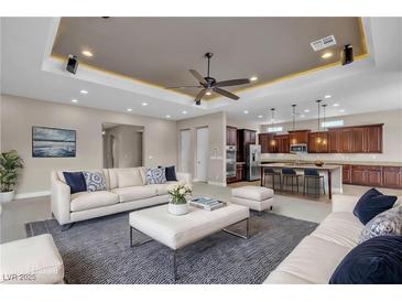 Open-concept living room showcasing modern furnishings and decor, plus an adjacent kitchen with a breakfast bar at 11274 Felice Cohn Ct, Las Vegas, NV 89179
