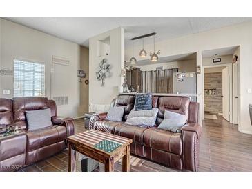 Inviting living room featuring wood floors and a comfortable brown leather sofa at 3150 Soft Breezes Dr # 2018, Las Vegas, NV 89128