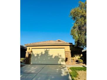 This home features a two-car garage with a concrete driveway and desert landscaping at 3538 Old Course St, Las Vegas, NV 89122