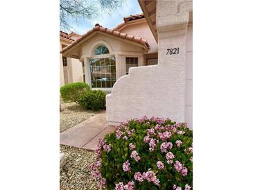 Charming home exterior with stucco walls, red tile roof, and colorful landscaping with pink flowers in the front at 7821 Desert Bell Ave, Las Vegas, NV 89128