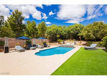 A refreshing pool area with lounge chairs and a manicured lawn provides a relaxing outdoor oasis at 11244 Playa Caribe Ave, Las Vegas, NV 89138