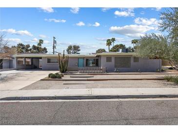 Charming single-story home showcasing xeriscaping, palm trees and a turquoise front door at 2205 Sombrero Dr, Las Vegas, NV 89169