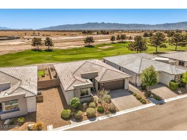 Inviting single-story home boasting desert landscaping and a tile roof, complemented by a lush green golf course backdrop at 4820 Se Clifftop Dr, Pahrump, NV 89061