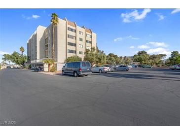 Attractive building with a large parking lot, mature trees, and well-maintained landscaping under a clear blue sky at 725 N Royal Crest Cir # 246, Las Vegas, NV 89169