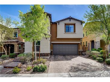 Two-story home with a well-manicured front yard and an attached two-car garage and brick driveway at 9921 Rams Leap Ave, Las Vegas, NV 89166