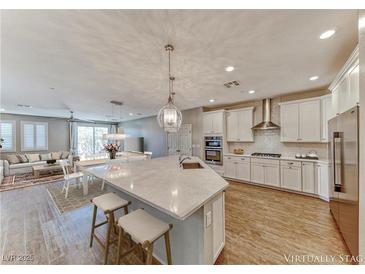 Bright, open kitchen with white cabinets, stainless steel appliances, and a large center island with seating at 2767 Flowing Breeze St, Henderson, NV 89044