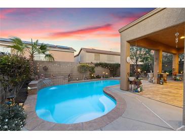 Inviting pool with a tanning ledge, water feature, and landscaped patio under a covered area, perfect for outdoor relaxation at 648 Sunrise Lake Pl, Henderson, NV 89002