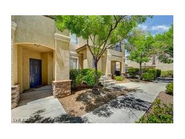 Inviting stucco home featuring desert landscaping with mature trees and bushes enhancing the curb appeal at 1713 Queen Victoria St # 104, Las Vegas, NV 89144