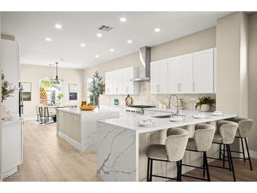 Bright kitchen with white cabinets, stainless steel appliances, and a large island with a marble waterfall countertop at 2264 Savannah River St, Henderson, NV 89044