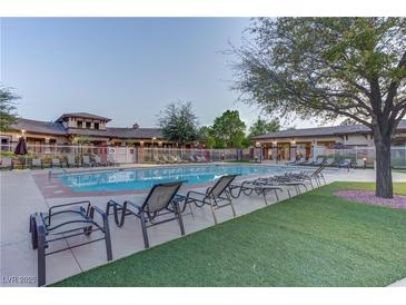 Community pool view with lounge chairs on concrete and artificial turf, surrounded by mature trees at 10422 Prairie Mountain Ave, Las Vegas, NV 89166