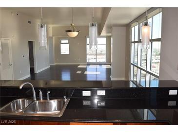 Modern kitchen featuring granite countertops, stainless steel sink, and a view of the living area with large windows at 150 N Las Vegas Blvd # 1217, Las Vegas, NV 89101