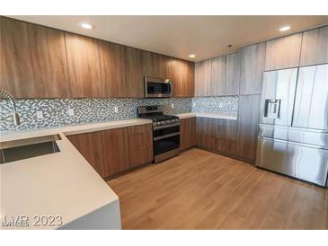 Modern kitchen with stainless steel appliances, tile backsplash, wood floors, and two-tone wood cabinets at 150 N Las Vegas Blvd # 2302, Las Vegas, NV 89101