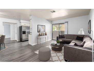 Comfortable living room features a large sectional sofa, decorative rug, and sliding glass door to outdoor balcony at 2451 N Rainbow Blvd # 1016, Las Vegas, NV 89108