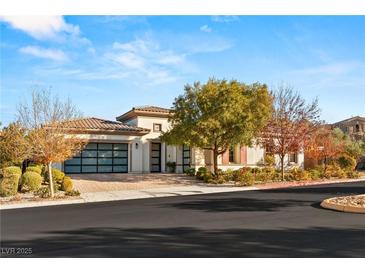 A single-story home shows off its tidy front yard and a three-car garage with contemporary design and desert landscaping at 28 Tea Olive Dr, Las Vegas, NV 89141