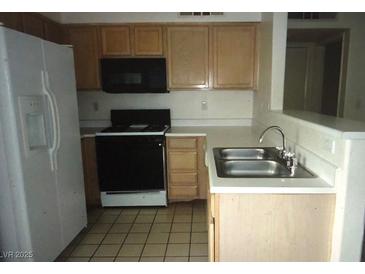 The kitchen has tile floors, black appliances and oak colored cabinets at 3041 Casey Dr # 101, Las Vegas, NV 89120