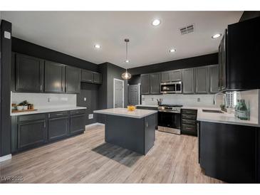Modern kitchen features gray cabinetry, stainless steel appliances, and center island with white countertops at 3409 Catherine Mermet Ave, North Las Vegas, NV 89081