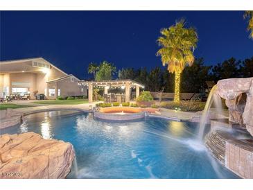 Custom pool with rock waterfall, spa, and swim up bar, all illuminated at twilight at 382 Chaplin Cove Ave, Las Vegas, NV 89183