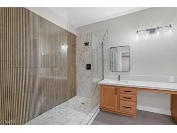Modern bathroom with a glass enclosed shower with tile surround and wood-look accent wall at 913 Duckhorn Ct # 201, Las Vegas, NV 89144