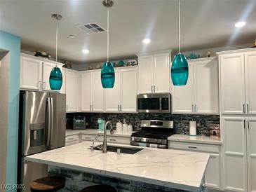 Modern kitchen featuring white cabinets, stainless steel appliances, and a large quartz island with pendant lighting at 965 Nevada State Dr # 35101, Henderson, NV 89002