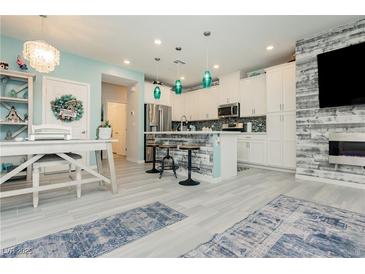 Bright kitchen features white cabinets, stainless steel appliances, large island with seating, and decorative blue pendant lights at 965 Nevada State Dr # 35101, Henderson, NV 89002