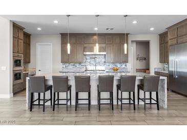 A gourmet kitchen features a large island, breakfast bar, stainless appliances, and ample counter space at 7477 Triple Knot Ct, Las Vegas, NV 89113