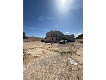 Spacious home with circular window, ample surrounding land, and a detached garage, set beneath a clear sky at 7475 Gilespie St, Las Vegas, NV 89123