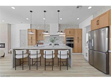 Modern kitchen features a marble island with seating, stainless steel appliances and light wood cabinets at 2317 Sierra Heights Dr, Las Vegas, NV 89134